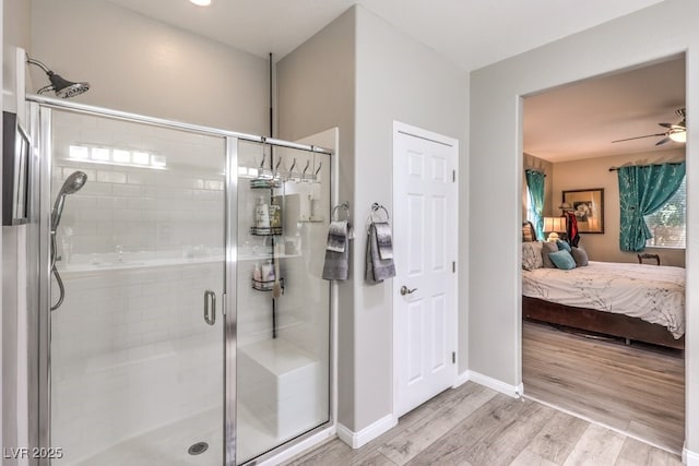 full bath with a shower stall, ensuite bath, a ceiling fan, wood finished floors, and baseboards