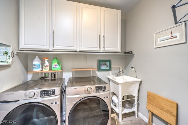 laundry area with baseboards, cabinet space, and washing machine and dryer