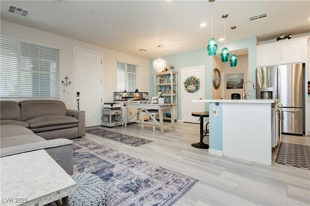 living area with baseboards, light wood-type flooring, recessed lighting, and visible vents