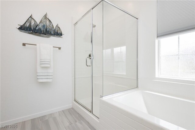 bathroom with baseboards, a bath, and a stall shower