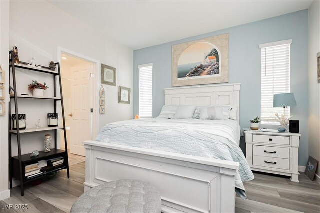 bedroom with light wood-type flooring, baseboards, and multiple windows
