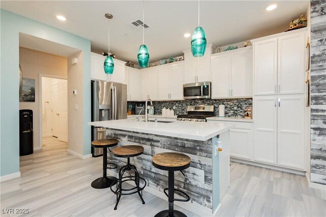 kitchen featuring visible vents, appliances with stainless steel finishes, a breakfast bar, and tasteful backsplash