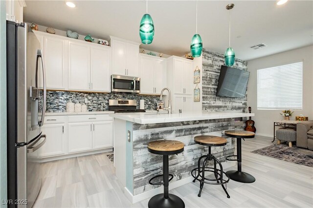 kitchen featuring visible vents, backsplash, white cabinets, and stainless steel appliances