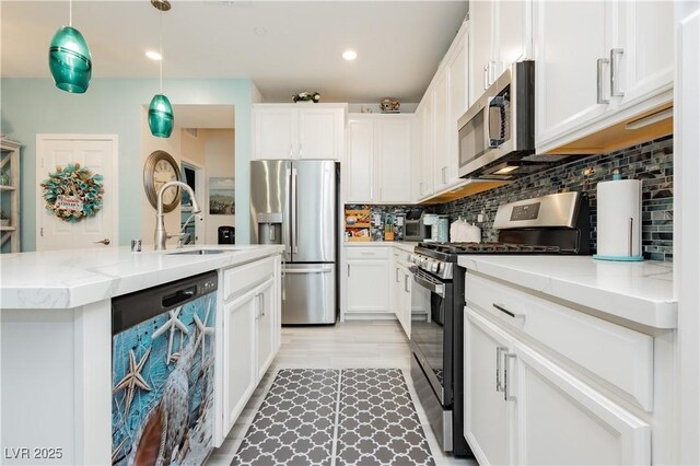 kitchen featuring a center island with sink, white cabinetry, tasteful backsplash, a sink, and stainless steel appliances