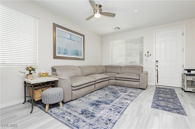 living area with baseboards, ceiling fan, light wood-style flooring, and visible vents