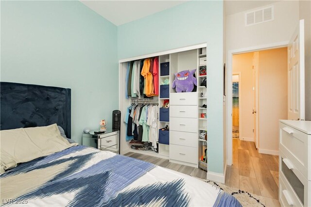 bedroom featuring baseboards, a closet, light wood-type flooring, and visible vents