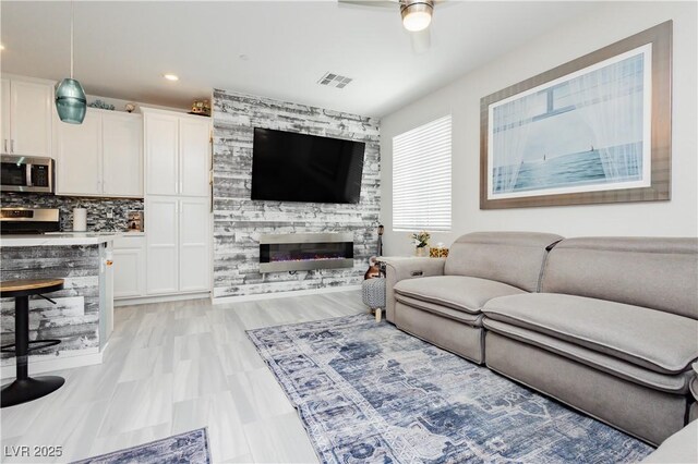 living area featuring a fireplace, a ceiling fan, recessed lighting, and visible vents