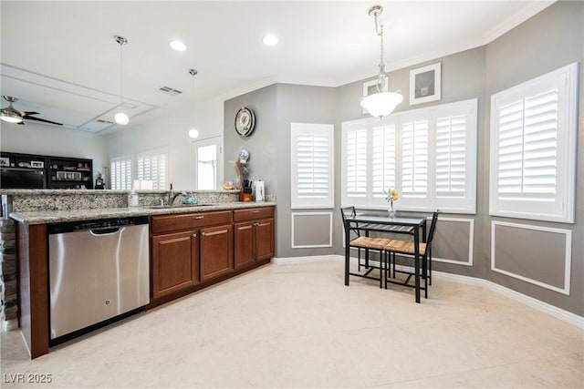 kitchen featuring brown cabinets, light stone counters, stainless steel dishwasher, a sink, and decorative light fixtures