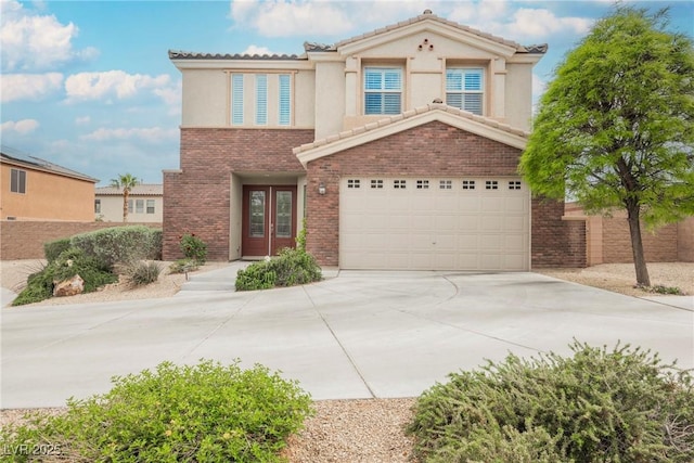 traditional home with french doors, driveway, brick siding, an attached garage, and stucco siding
