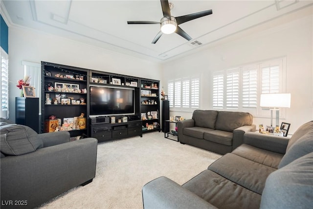 living area with ceiling fan, visible vents, carpet flooring, and ornamental molding