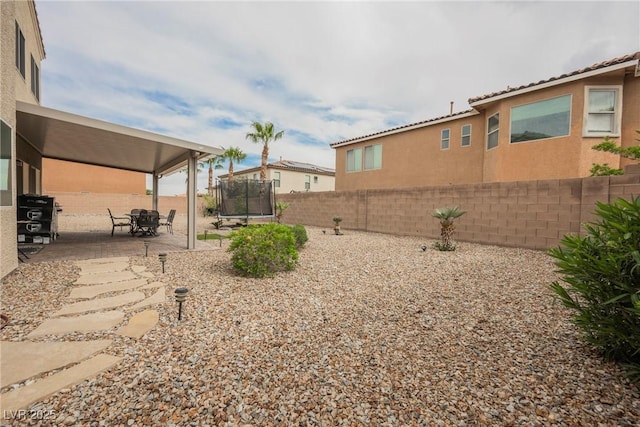 view of yard with a patio area, a fenced backyard, and a trampoline