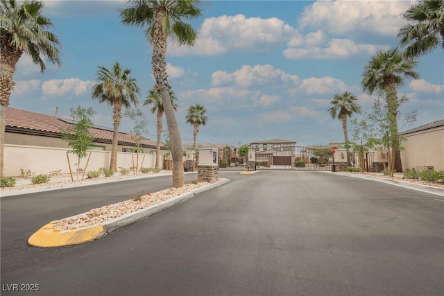view of street with a gate, a residential view, a gated entry, and curbs