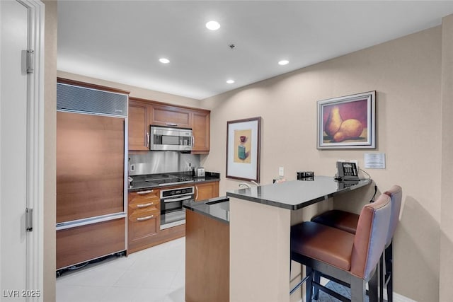 125 E Harmon Ave Unit 2220, Las Vegas, NV 89109 - kitchen featuring appliances with stainless steel finishes, dark countertops, a kitchen bar, a sink, and a peninsula