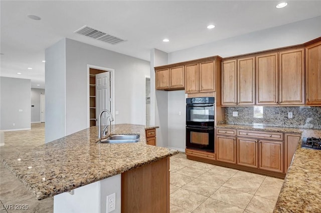 kitchen with backsplash, visible vents, light stone countertops, a sink, and black appliances