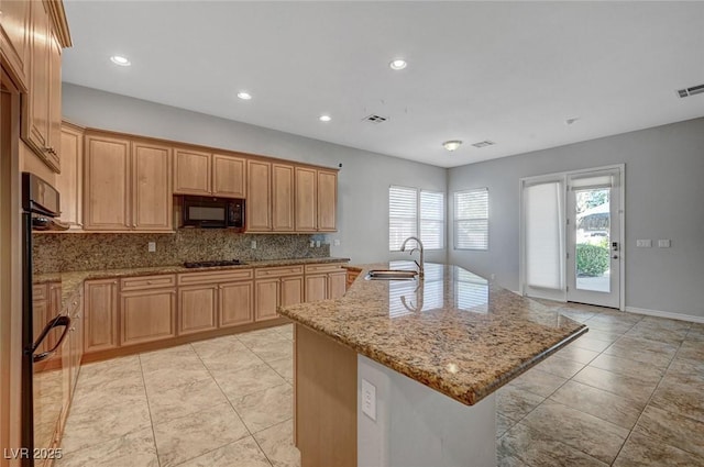 kitchen featuring gas cooktop, decorative backsplash, black microwave, a sink, and light stone counters