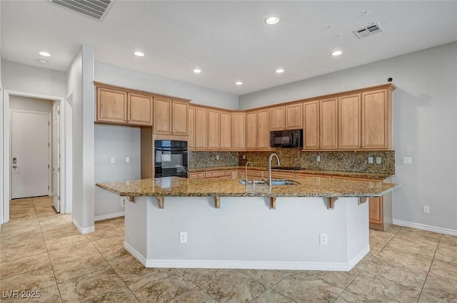 kitchen featuring backsplash, stone countertops, visible vents, and black appliances