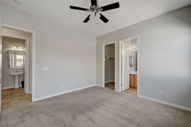 unfurnished bedroom with a walk in closet, baseboards, and ensuite bath