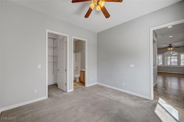 unfurnished bedroom with baseboards, connected bathroom, a spacious closet, and light colored carpet