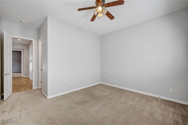 carpeted spare room featuring baseboards and ceiling fan