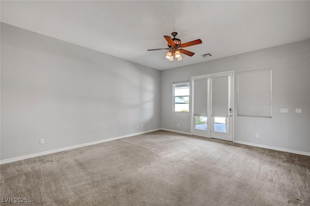 carpeted spare room with visible vents, baseboards, and ceiling fan