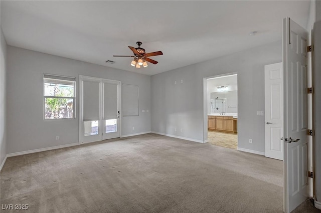 carpeted spare room with baseboards, ceiling fan, and visible vents