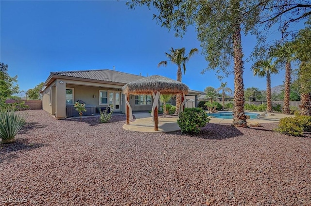 rear view of house with a tile roof, a fenced in pool, fence, a patio, and stucco siding