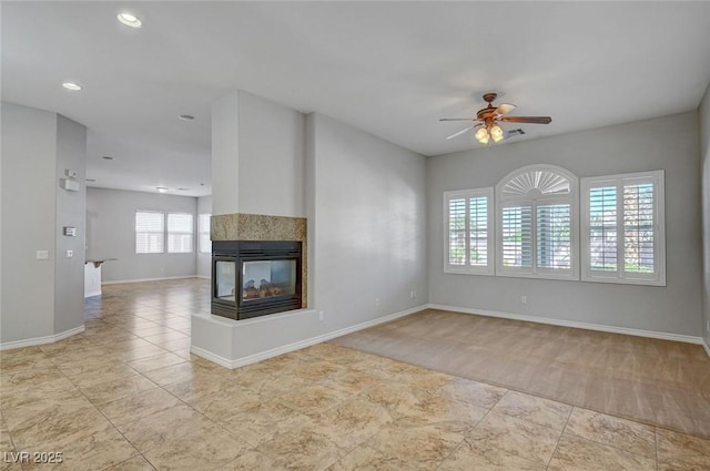 unfurnished living room featuring carpet flooring, baseboards, recessed lighting, a ceiling fan, and a multi sided fireplace