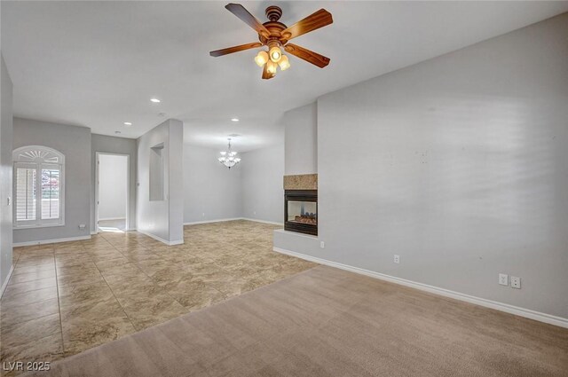 unfurnished living room featuring a multi sided fireplace, recessed lighting, baseboards, and ceiling fan with notable chandelier
