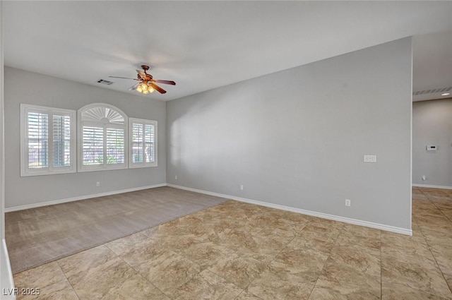 empty room featuring baseboards, ceiling fan, and visible vents