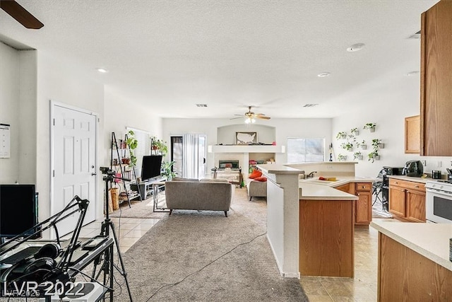 2509 April Breeze Ln, Henderson, NV 89002 - kitchen featuring a peninsula, white gas range, a ceiling fan, and plenty of natural light