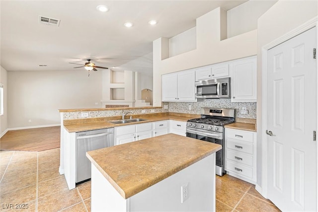 9539 Iris Flat Ct, Las Vegas, NV 89178 - kitchen with stainless steel appliances, a sink, a ceiling fan, a peninsula, and white cabinets