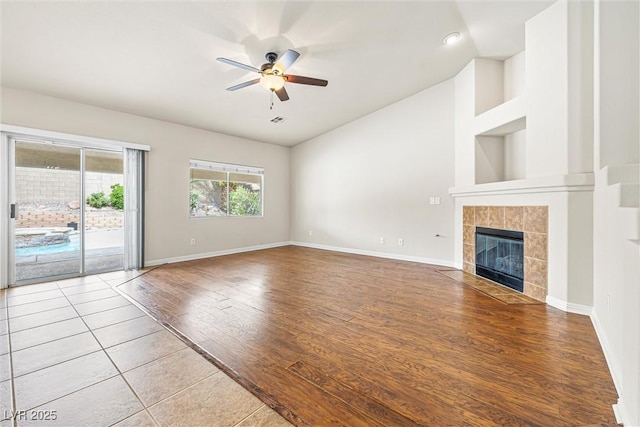 9539 Iris Flat Ct, Las Vegas, NV 89178 - unfurnished living room with lofted ceiling, a ceiling fan, baseboards, wood finished floors, and a tile fireplace