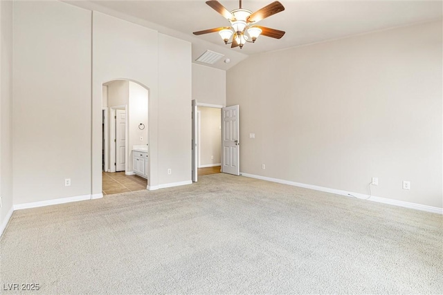 9539 Iris Flat Ct, Las Vegas, NV 89178 - unfurnished bedroom with arched walkways, light carpet, baseboards, high vaulted ceiling, and connected bathroom