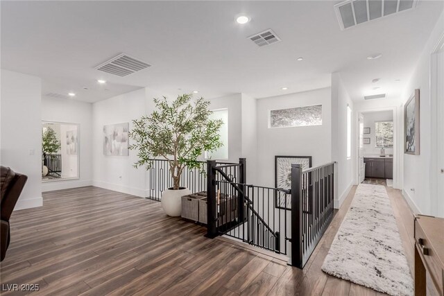 hallway featuring an upstairs landing, wood finished floors, recessed lighting, and baseboards