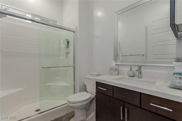 bathroom featuring a stall shower, toilet, and vanity