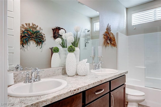full bath featuring a sink, toilet, double vanity, and a healthy amount of sunlight