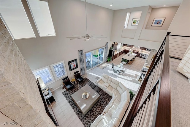 living room with a ceiling fan and a high ceiling