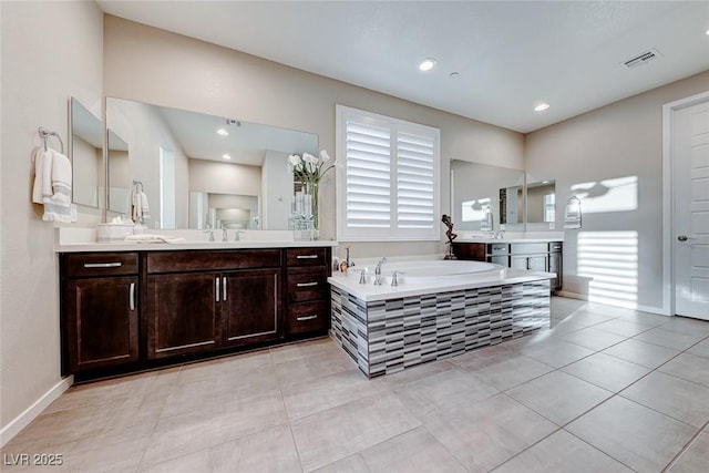 bathroom featuring visible vents, a bath, two vanities, and tile patterned floors