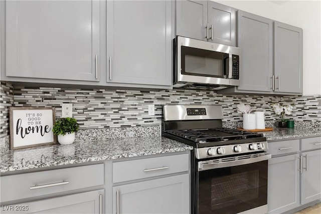 5317 Golden Melody Ln, North Las Vegas, NV 89081 - kitchen featuring appliances with stainless steel finishes, tasteful backsplash, light stone counters, and gray cabinetry