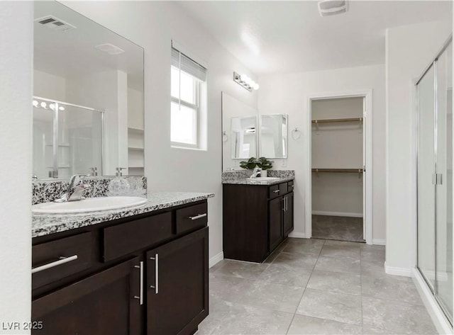 5317 Golden Melody Ln, North Las Vegas, NV 89081 - bathroom featuring a stall shower, a spacious closet, two vanities, and baseboards