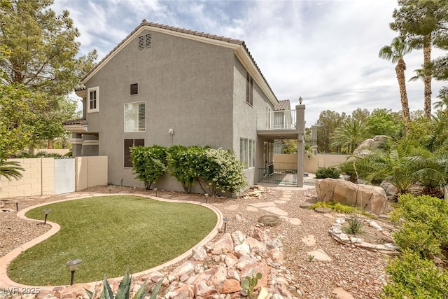 9705 Floweret Ave, Las Vegas, NV 89117 - view of side of home with a gate, stucco siding, a balcony, and a tiled roof