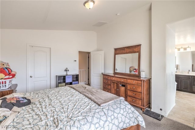 bedroom featuring connected bathroom, light colored carpet, and vaulted ceiling