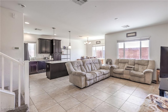 living area with light tile patterned floors, an inviting chandelier, visible vents, and stairs