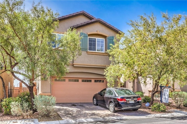 view of front of home with a garage, driveway, fence, and stucco siding