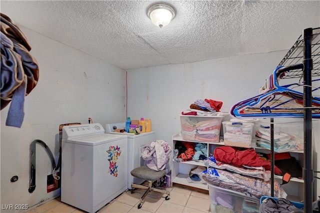 washroom with light tile patterned floors, washing machine and dryer, a textured ceiling, and laundry area