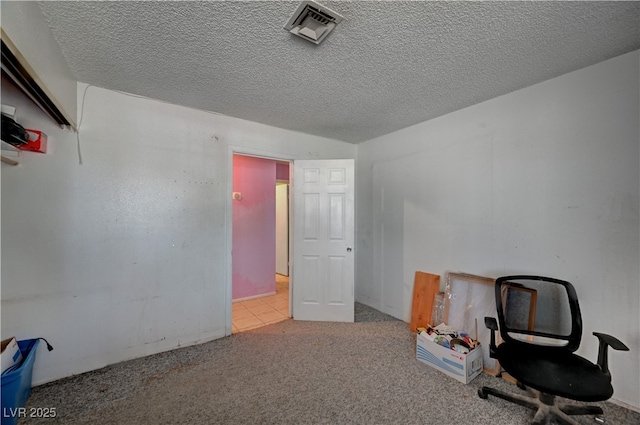 unfurnished office with a textured ceiling, carpet, and visible vents