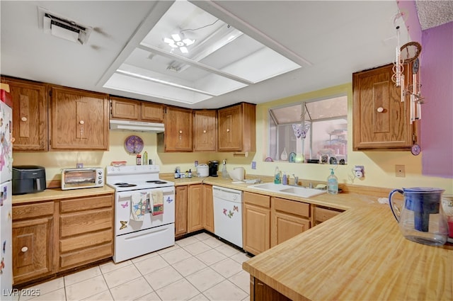 kitchen featuring a sink, light countertops, white appliances, under cabinet range hood, and light tile patterned flooring