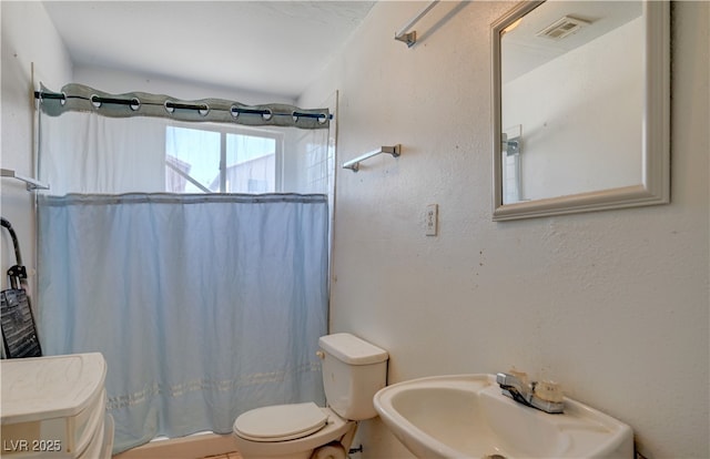 full bath featuring toilet, a shower with curtain, a sink, and visible vents