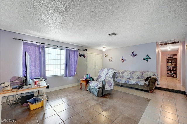 tiled living room with visible vents, a textured ceiling, and baseboards