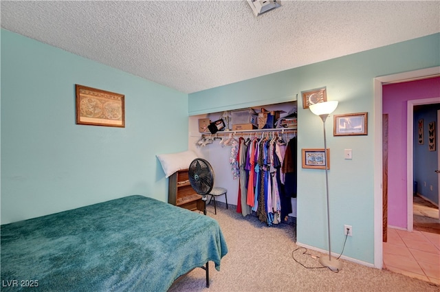 carpeted bedroom with a textured ceiling, a closet, and baseboards